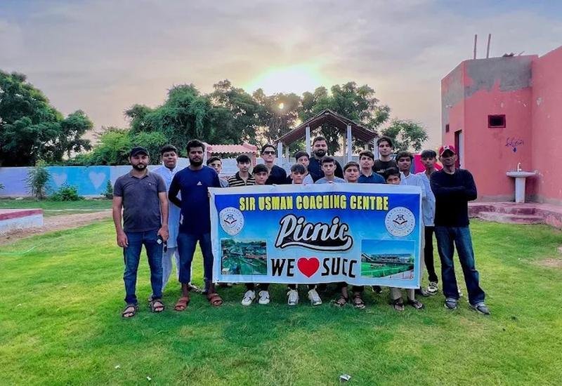 SUCC students and teachers at the academy picnic holding the Sir Usman Coaching Centre banner